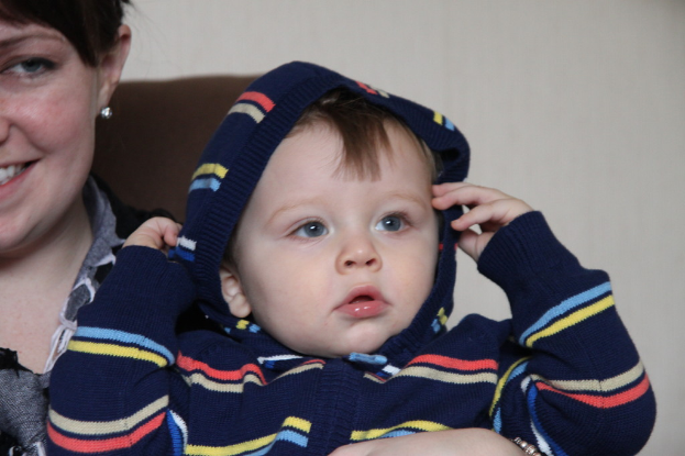 Eine Frau hält ein Kind im Arm und steht vor einer Wand.