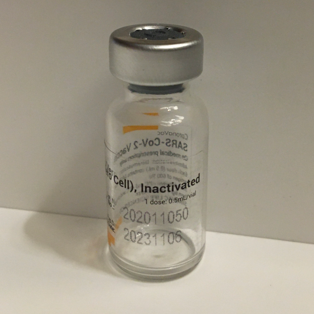 Ein weißes Fläschchen mit der Aufschrift "Inaktivierter S-Voc-2A2", das eine klare Flüssigkeit enthält und auf einem weißen Tisch steht.