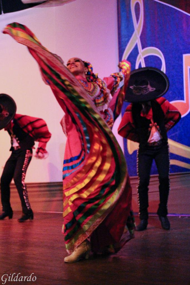 Menschen auf einer Bühne in Kostümen mit einem Vorhang mit einem Bild im Hintergrund.