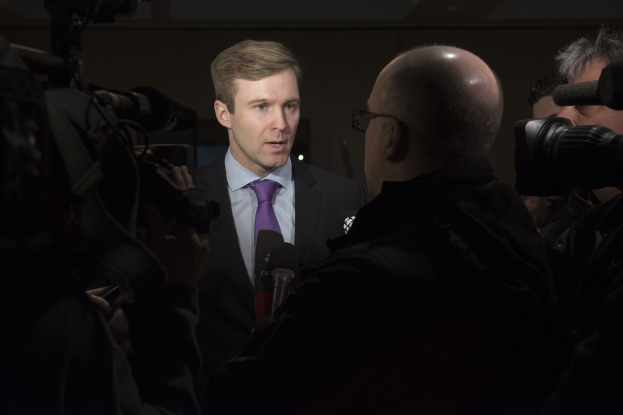Ein Mann im Anzug mit Brille spricht in ein Mikrofon, während zwei Kameramänner aufnehmen.