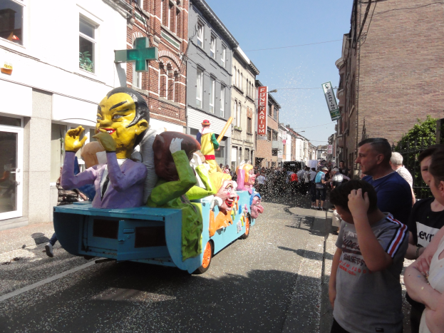 Eine Gruppe von Menschen auf einem bunt verzierten Spielzeug-Schauwagen bei einem Umzug.