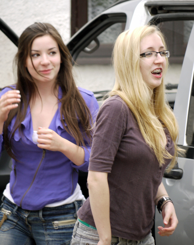 Frauen vor einem Auto, einer Wand und einem Fenster im Hintergrund.