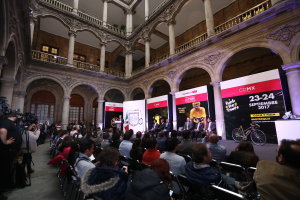 Eine Gruppe von Menschen sitzt an einem Tisch mit einem Podium und einem Mikrofon vor einer Menge, Kameras und Bannern während einer Pressekonferenz für das CDMX 2017-Event.