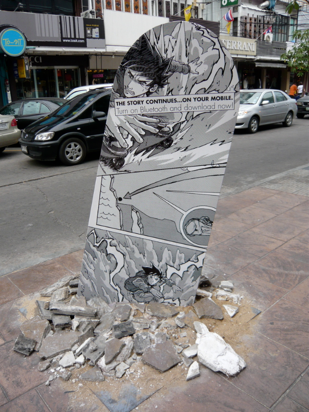Ein Schild auf einem Fußweg mit Autos auf der benachbarten Straße neben einem Gebäude.