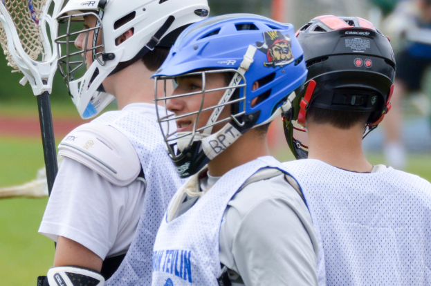 Drei Spieler in weißen Jacken und Helmen, mit unscharfem Hintergrund.