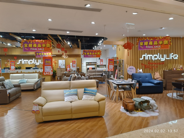 Ein Möbelgeschäftsinneres mit verschiedenen Sofas, Tischen, Stühlen, Hockern und anderen Möbelstücken, beleuchtet von Deckenlampen, mit Texttafeln in Chinesisch und einem Wasserzeichen im rechten unteren Eck.