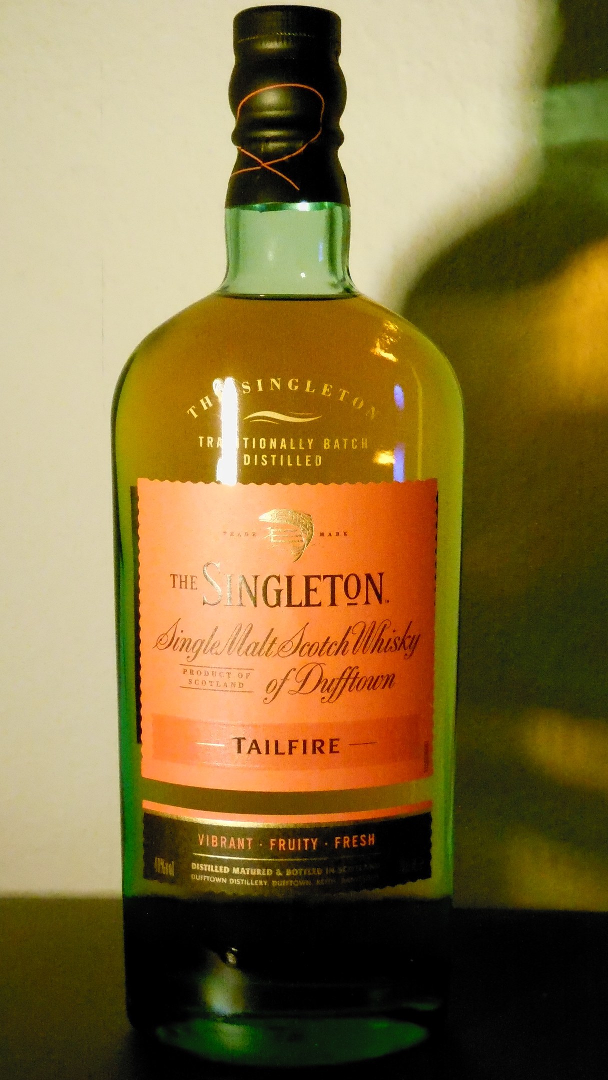 Tiefer Bernstein Singleton of Dufftown Tailfire Single Malt Scotch Whisky Flasche mit schwarzem Etikett, das ein Löwen- und Schlosswappen zeigt, auf einem Tisch.